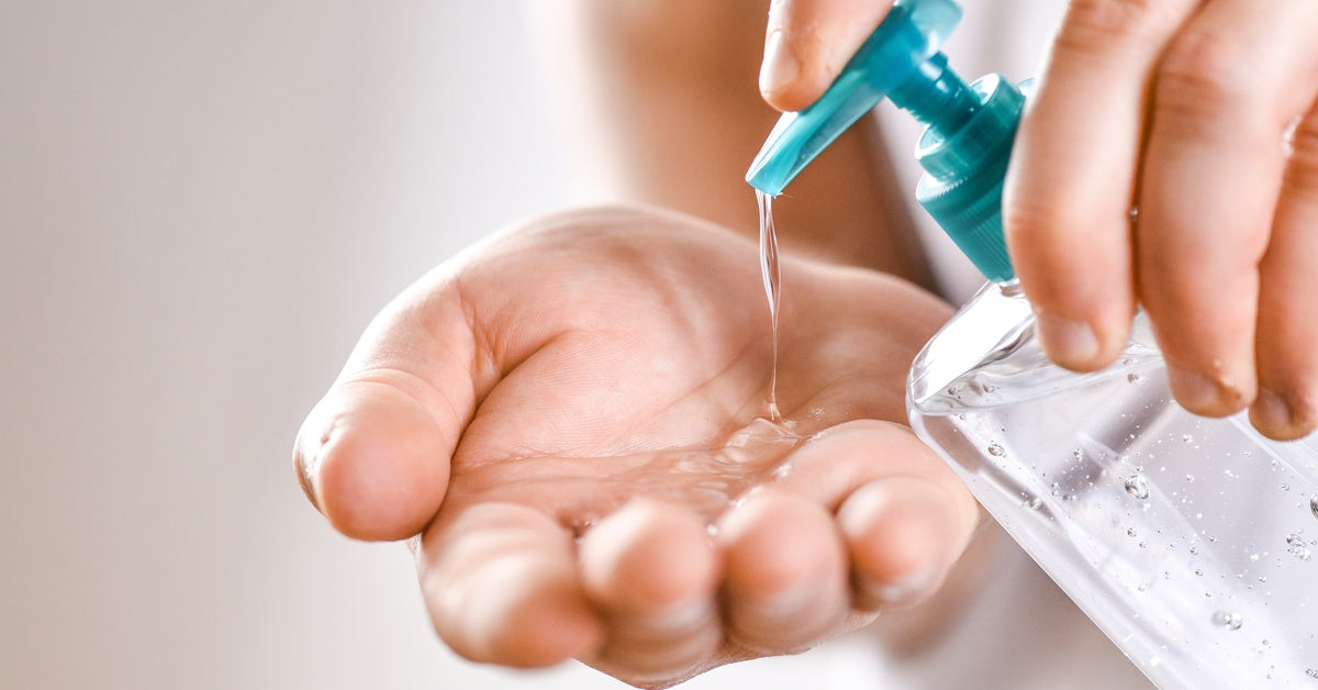 A close-up of someone pumping hand sanitizer into their hand. The sanitizer bottle is clear with a blue pump.