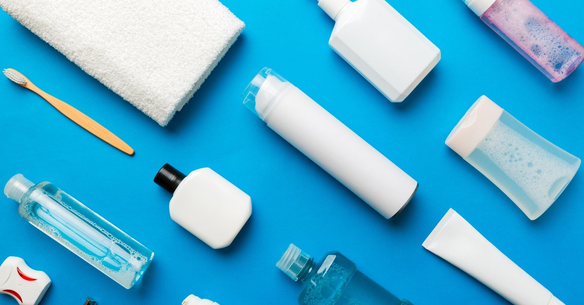 A close-up of toiletries lying on a blue table. The items include soap, mouthwash, a toothbrush, and other related items.