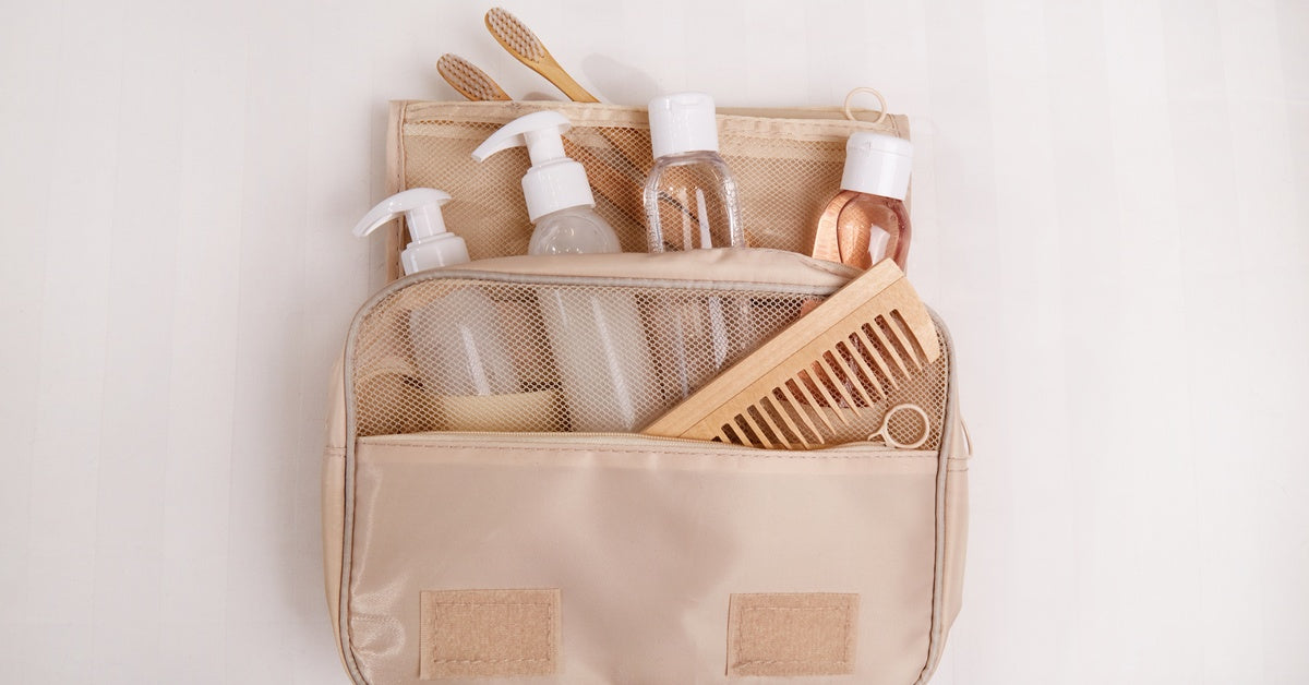 A tan toiletry bag is packed with essential personal hygiene items and is neatly displayed on a white surface.