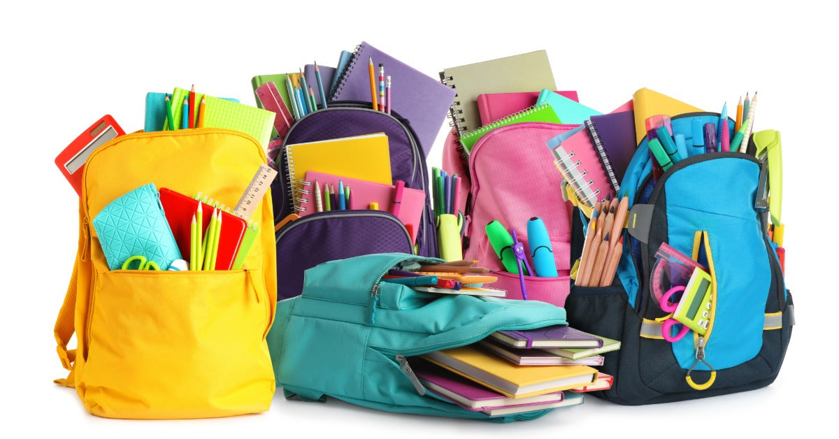 Colorful backpacks filled with school supplies, notebooks, pencils, scissors, and books on a white background.