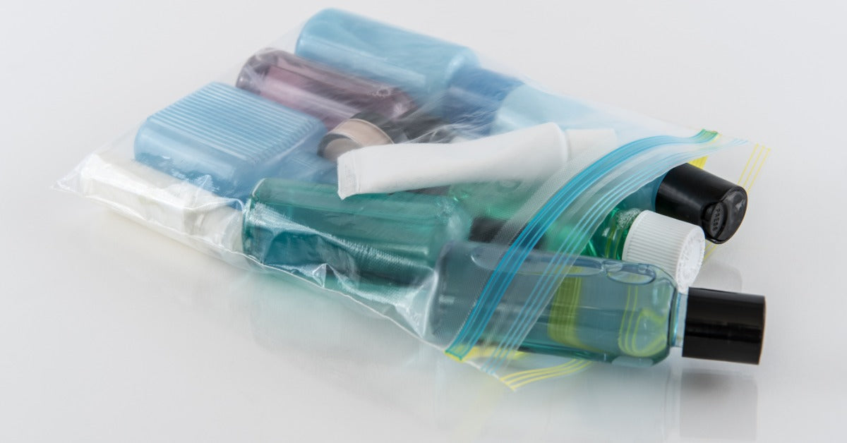 Travel-size toiletries, including bottles, soap, and toothpaste, are packed inside a clear zip-top plastic bag.